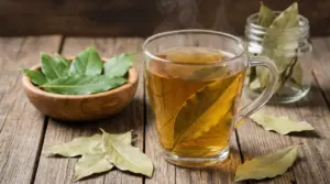 Tazza di infuso caldo con foglie di alloro su tavolo in legno